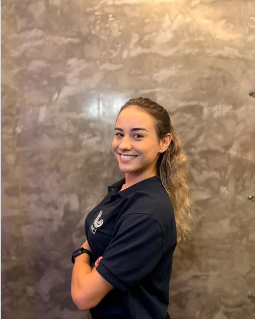 Maria Luíza da Costa Siqueira sorrindo, de perfil, com o uniforme preto de atendimento.